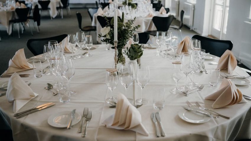 A beautifully arranged dining table setup for a wedding reception with elegant tableware and floral centerpiece.