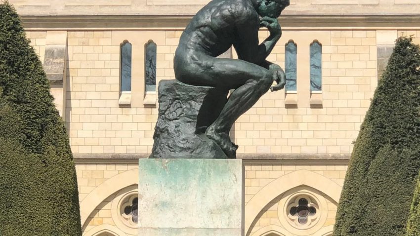The iconic Thinker statue in Paris in front of a historic building.